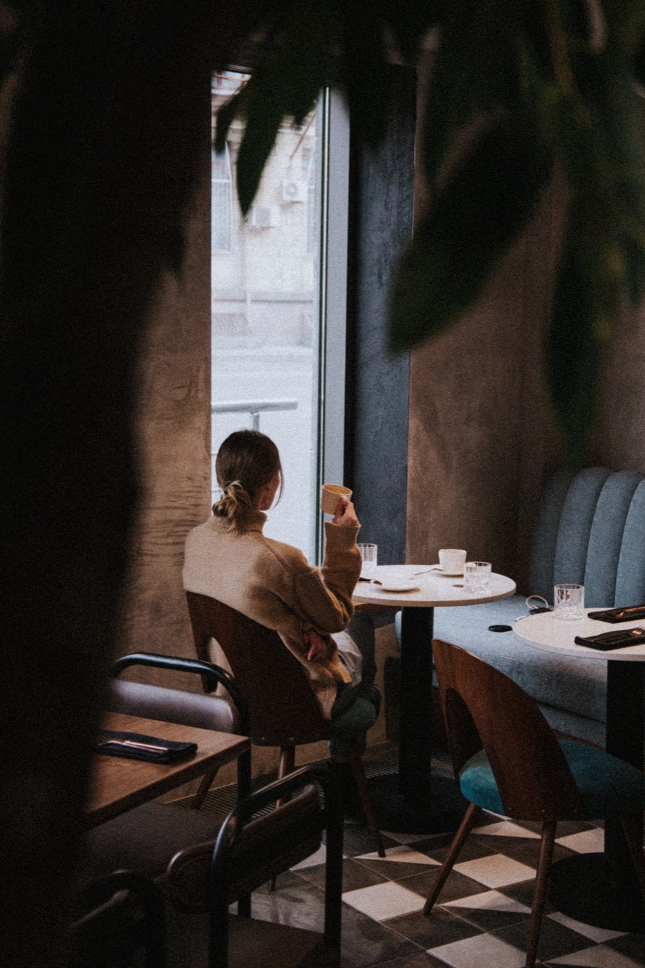 A guest with a cup of coffee at the window of a small café
